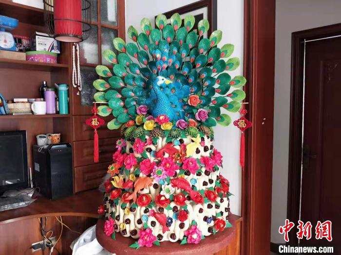  在卫兴安家中的一处角落，三层花馍顶端那只色彩艳丽的蓝孔雀让人惊叹不已，每片羽毛上的纹路都看得很清楚。 杨佩佩 摄