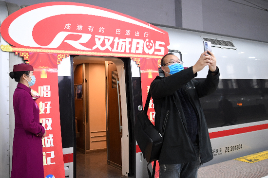  成渝间实现高铁公交化运营1小时直达，这是乘客在重庆沙坪坝站开往成都东站的G8608次“复兴号”高铁列车前留影（2020年12月24日摄）。新华社记者 唐奕 摄